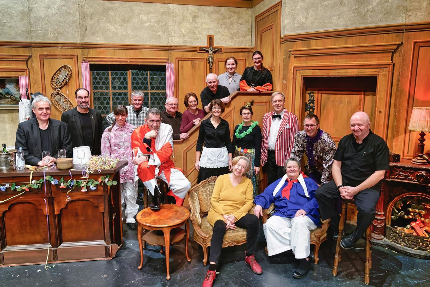 Läggerli 2020: Gruppenbild des Ensembles in der holzgetäfelten Stube des Bühnenbilds.